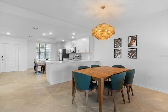 dining area featuring sink, light tile patterned floors, and a tray ceiling