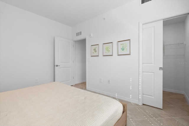 bedroom featuring a spacious closet, light tile patterned floors, and a closet