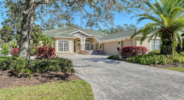 12471 Natureview Cir, Bradenton, FL 34212 - view of front of home featuring an attached garage, stucco siding, decorative driveway, and a tiled roof