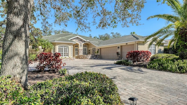 12471 Natureview Cir, Bradenton, FL 34212 - ranch-style home featuring an attached garage, stucco siding, a tiled roof, decorative driveway, and stone siding