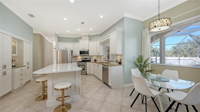 12471 Natureview Cir, Bradenton, FL 34212 - kitchen featuring appliances with stainless steel finishes, a sink, white cabinets, a kitchen island, and light tile patterned floors