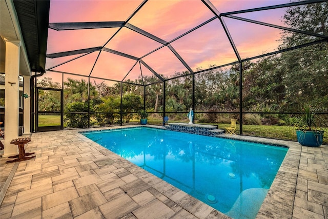 pool at dusk with a lanai and a patio area