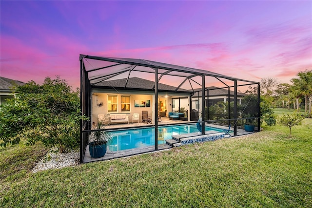 pool at dusk with a patio, a lanai, a yard, and outdoor lounge area