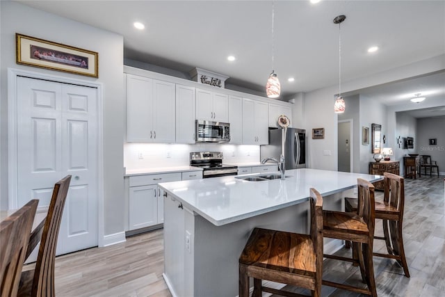 kitchen featuring pendant lighting, sink, a kitchen bar, a kitchen island with sink, and stainless steel appliances