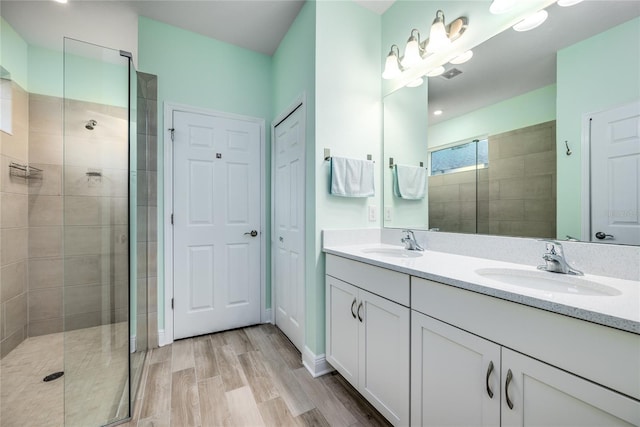 bathroom with hardwood / wood-style flooring, vanity, and a tile shower