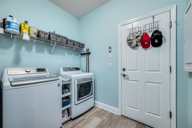 washroom with light hardwood / wood-style floors, washer and dryer, and a textured ceiling