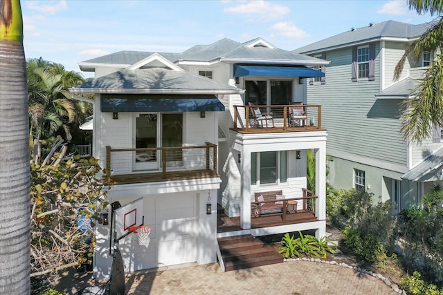 rear view of house featuring a garage and a balcony