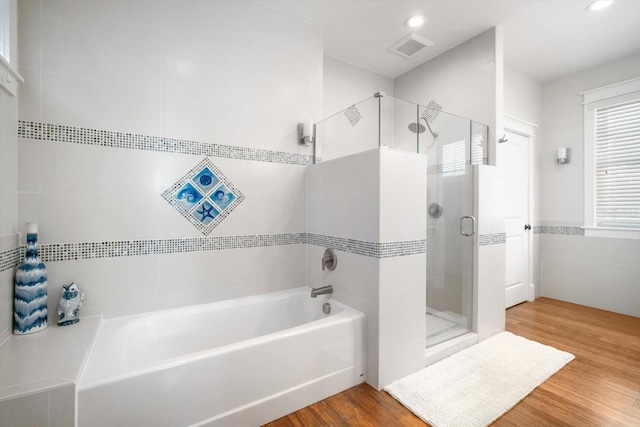 bathroom featuring hardwood / wood-style flooring, separate shower and tub, and tile walls