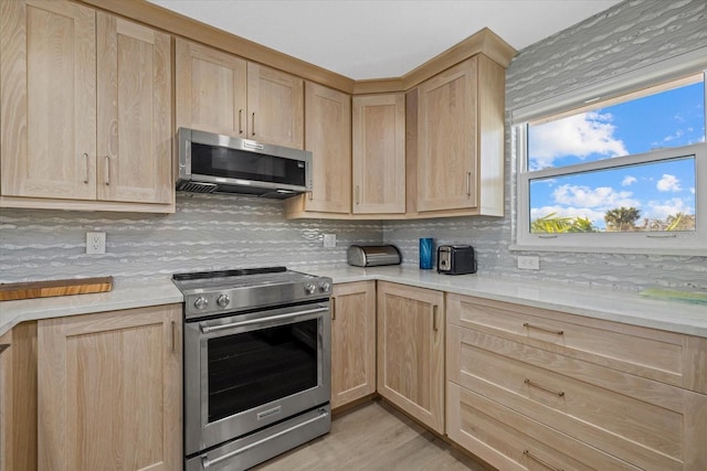 kitchen featuring tasteful backsplash, stainless steel appliances, light stone countertops, light brown cabinets, and light hardwood / wood-style flooring