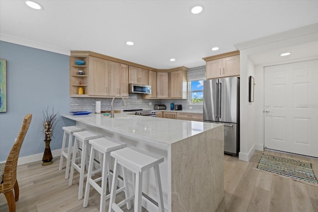 kitchen featuring sink, light stone counters, light brown cabinets, kitchen peninsula, and stainless steel appliances