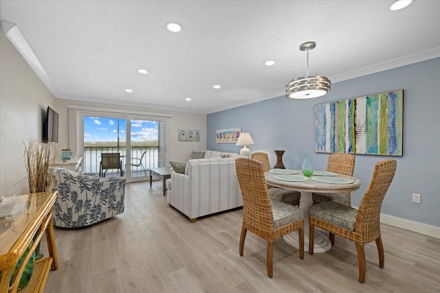 dining area with crown molding and light hardwood / wood-style flooring