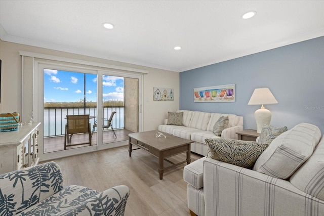 living room with light hardwood / wood-style flooring, ornamental molding, and a water view