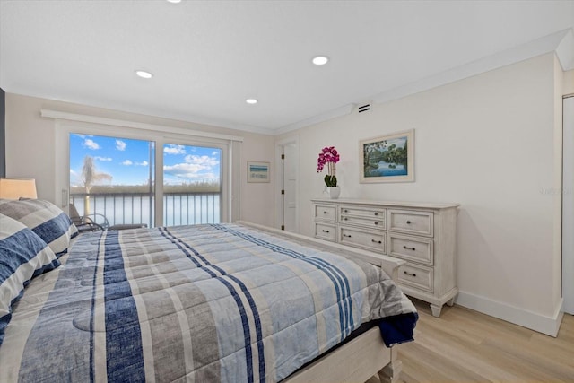 bedroom with ornamental molding, a water view, and light wood-type flooring