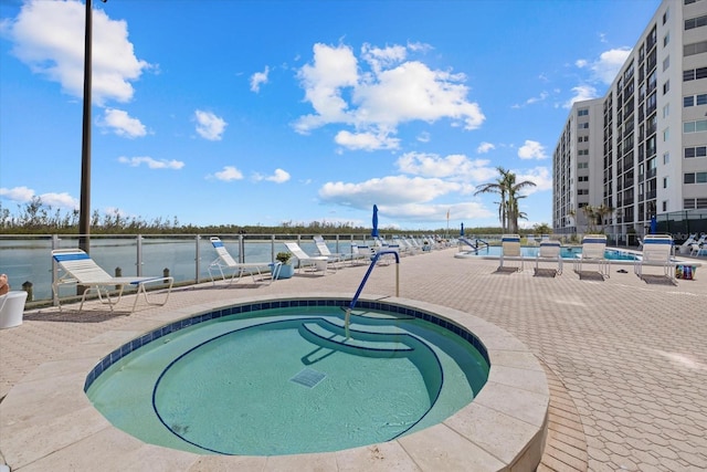 view of pool with a patio area, a hot tub, and a water view