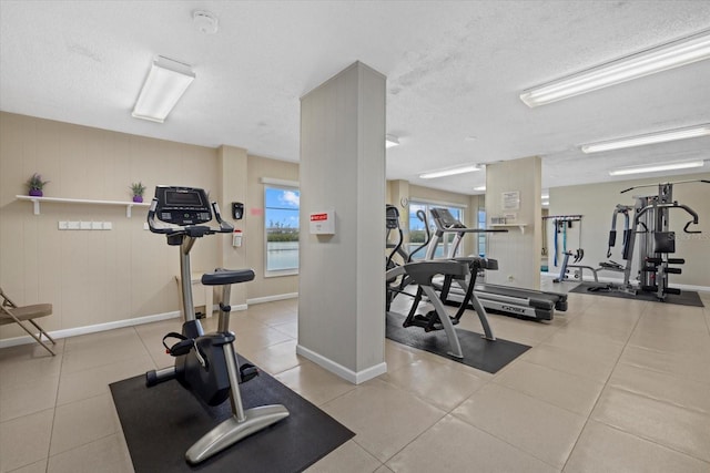 gym with a textured ceiling and light tile patterned flooring