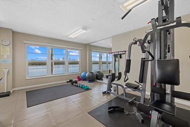 exercise area with a water view and a textured ceiling