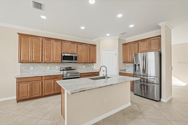 kitchen with light tile patterned flooring, sink, a kitchen island with sink, light stone counters, and stainless steel appliances