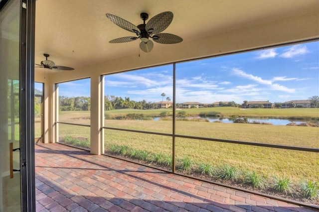 unfurnished sunroom with a water view and ceiling fan