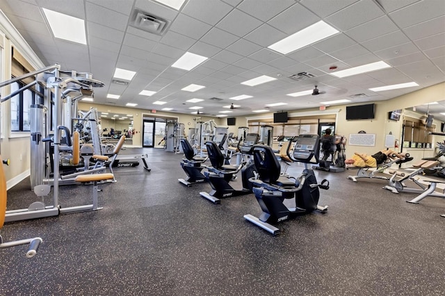 gym with a paneled ceiling and a healthy amount of sunlight