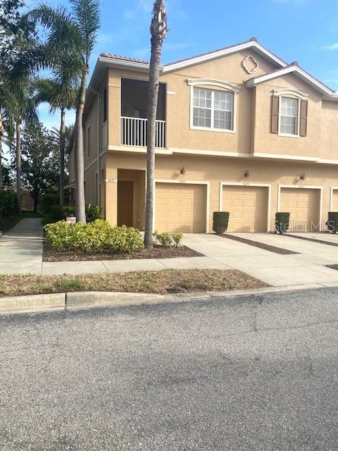 multi unit property featuring driveway, an attached garage, and stucco siding