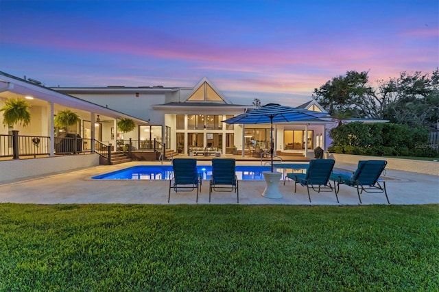 pool at dusk with a yard and a patio area