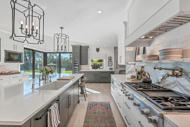 kitchen featuring sink, white cabinetry, hanging light fixtures, a spacious island, and a notable chandelier