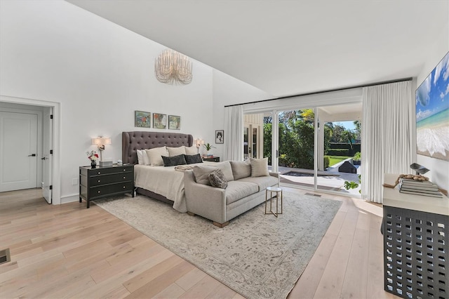 bedroom featuring wood-type flooring, a towering ceiling, and access to outside