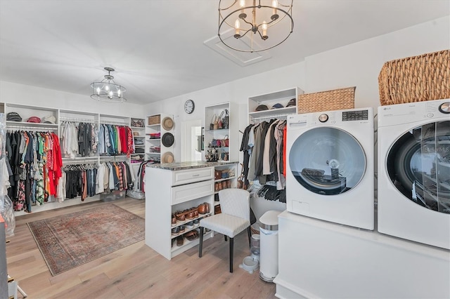 laundry room with washing machine and clothes dryer, light wood-type flooring, and a notable chandelier