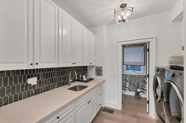 laundry area featuring light hardwood / wood-style floors, cabinets, washer and clothes dryer, and sink