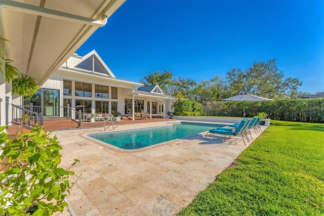 view of pool with a wooden deck, a lawn, and a patio