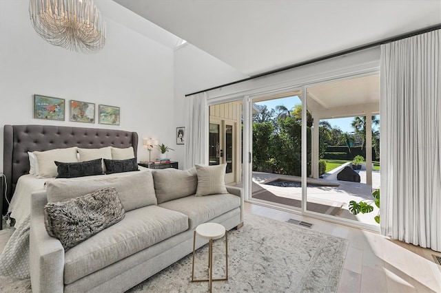 bedroom with access to exterior, wood-type flooring, and a high ceiling