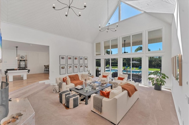 living room with plenty of natural light, light colored carpet, a notable chandelier, and high vaulted ceiling