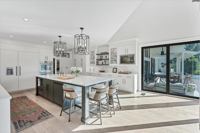 kitchen featuring a spacious island, decorative light fixtures, oven, and white cabinets