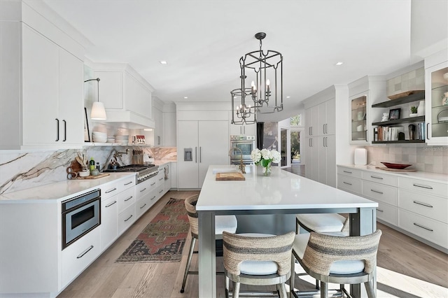 kitchen featuring a breakfast bar area, white cabinetry, stainless steel appliances, a center island, and decorative light fixtures