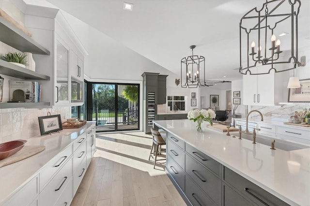 kitchen featuring white cabinetry, pendant lighting, a chandelier, and light hardwood / wood-style floors