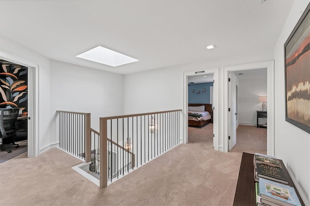 hallway with light carpet and a skylight