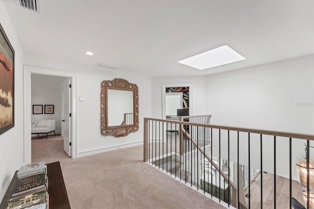 hall featuring light colored carpet and a skylight