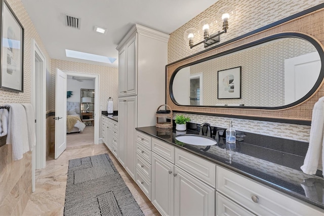 bathroom featuring french doors, vanity, and a skylight