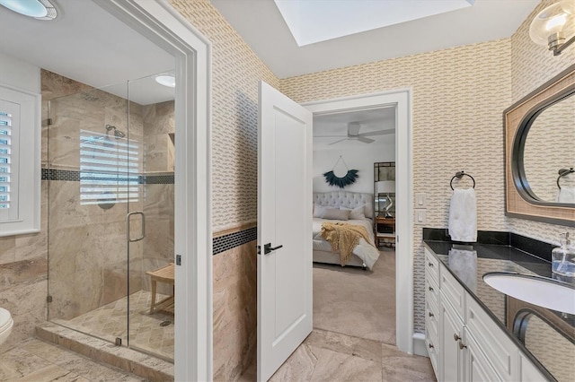 bathroom featuring vanity, a skylight, a shower with shower door, and toilet