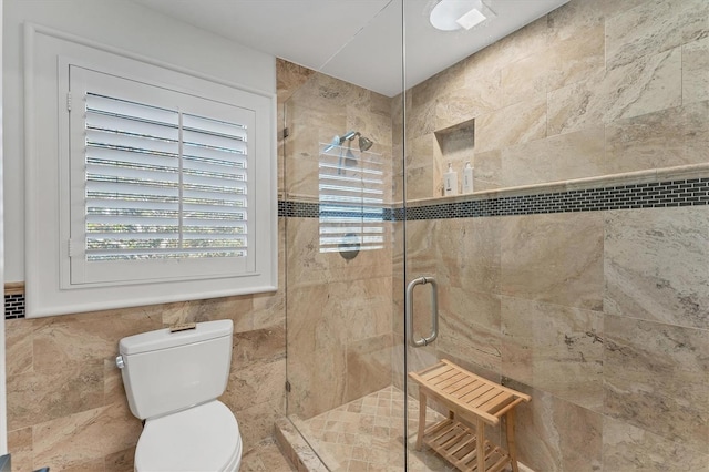 bathroom featuring tile walls, a shower with door, and toilet