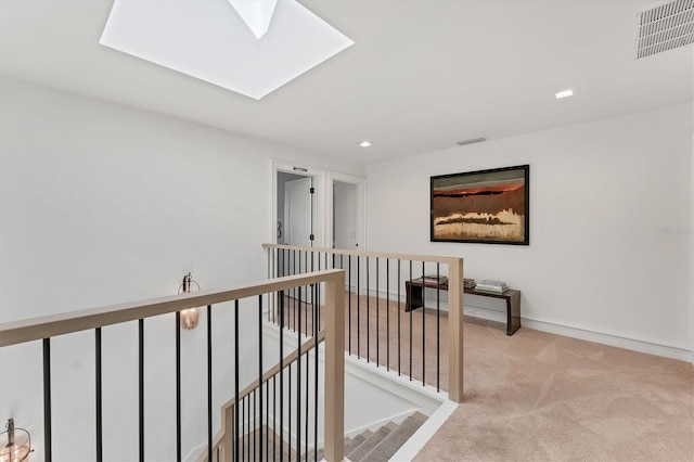 corridor with a skylight and light carpet