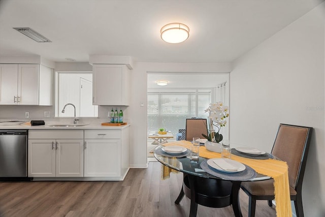 kitchen featuring stainless steel dishwasher, sink, light hardwood / wood-style flooring, and white cabinets