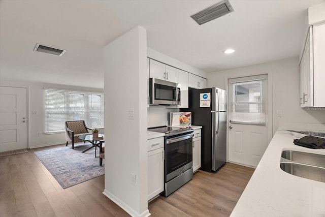 kitchen featuring white cabinetry, sink, light hardwood / wood-style flooring, and stainless steel appliances