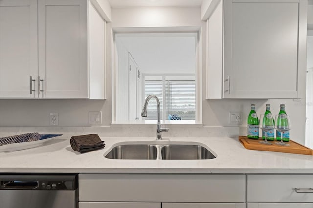 kitchen with light stone counters, dishwasher, sink, and white cabinets