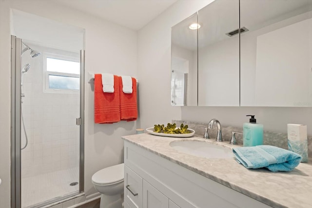 bathroom featuring vanity, toilet, and a shower with shower door