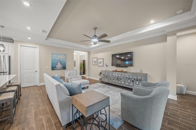 living room with a tray ceiling, ornamental molding, and ceiling fan