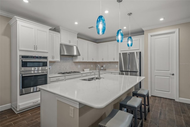 kitchen with sink, appliances with stainless steel finishes, white cabinets, and a center island with sink