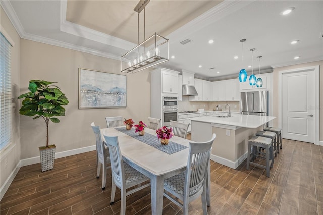 dining space featuring sink, a tray ceiling, and ornamental molding