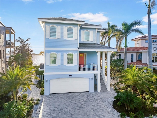 coastal home featuring a garage, stairway, and decorative driveway