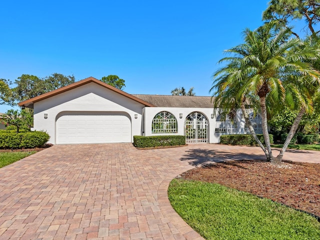 view of front facade with a garage, decorative driveway, and stucco siding